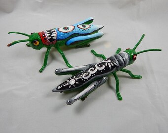 Grasshoppers with miniature paintings on them. Upcycled toy bugs.