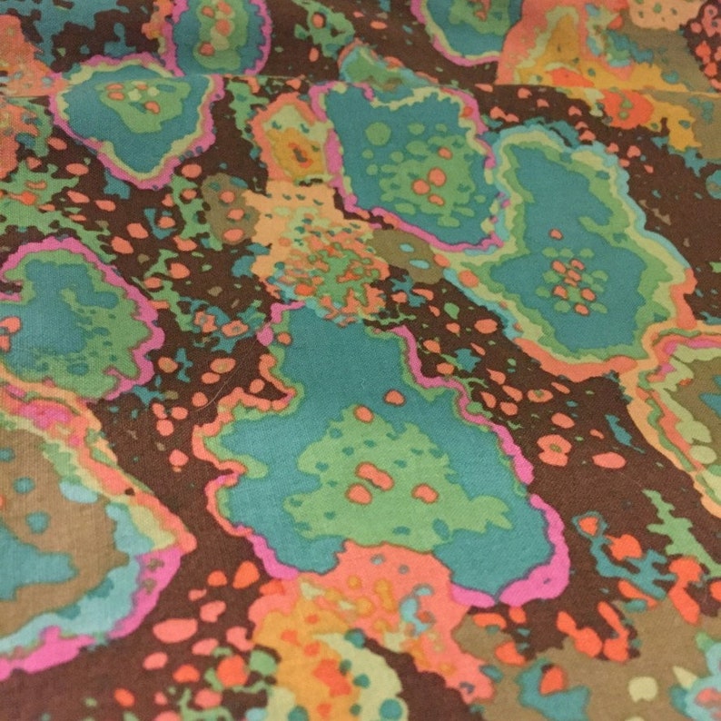 May include: Abstract fabric with a brown background and a colorful pattern of teal, pink, orange, and green. The pattern resembles a series of overlapping circles.