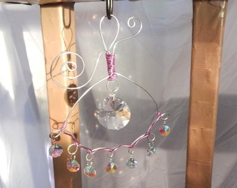 Suncatcher crystals with an abstract wire design hanger. Purple eye with rainbow disc prism.