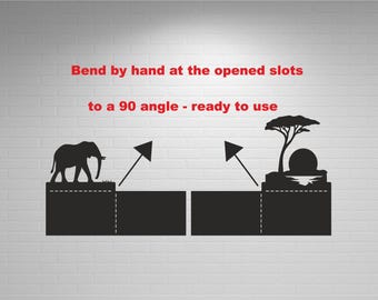 May include: Black silhouette design featuring an elephant and a tree with a sunset. The text reads "Bend by hand at the opened slots to a 90 angle - ready to use". The design is on a white brick wall.