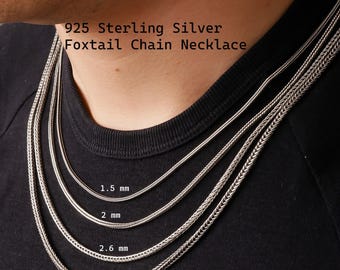 May include: A 925 sterling silver foxtail chain necklace shown in four different thicknesses: 1.5 mm, 2 mm, 2.6 mm, and 3.3 mm. The text 925 Sterling Silver Foxtail Chain Necklace is visible above the silver chains against a black shirt.