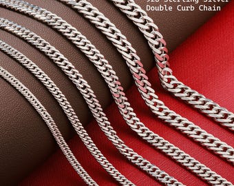 May include: A collection of 925 sterling silver double curb chains of varying thicknesses arranged in parallel. The chains feature a polished metallic finish with interlocking links. The text 925 Sterling Silver Double Curb Chain is visible.