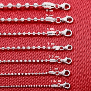 May include: Seven silver ball chains of varying thicknesses, ranging from 1.5 mm to 8 mm, each featuring a lobster claw clasp. The chains are arranged horizontally, with labels indicating their specific diameters in millimeters.