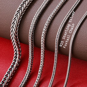 May include: Four silver foxtail chains of varying thicknesses arranged vertically. The chains feature a braided, woven metal link design with a polished finish. The text 925 Sterling Silver Foxtail Chain is printed in white on the right side.