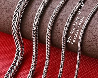 May include: Four silver foxtail chains of varying thicknesses arranged vertically. The chains feature a braided, woven metal link design with a polished finish. The text 925 Sterling Silver Foxtail Chain is printed in white on the right side.