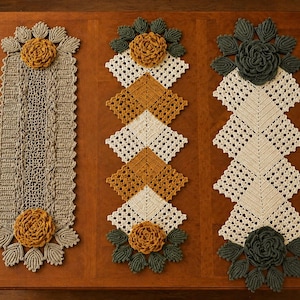 May include: Three handmade crochet table runners in shades of beige, mustard yellow, and olive green. Each runner features a floral design at both ends. The runners are displayed on a wooden table.