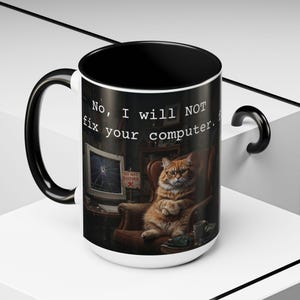 May include: A white ceramic mug with a black interior and handle. The mug features a humorous design of a cat wearing glasses, sitting in a chair, with the text "No, I will NOT fix your computer."