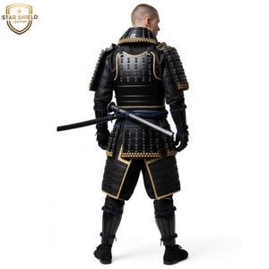 May include: Black and gold samurai armor with a katana. The armor features intricate detailing and a traditional design. The Star Shield Leather logo is visible in the upper left corner. The samurai armor is a full body suit.