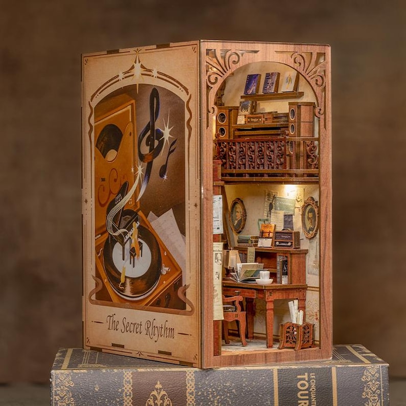 May include: A wooden miniature bookshelf with a music theme. The left side features a vintage record player and the text "The Secret Rhythm." The right side shows a detailed interior with a desk, books, and a small radio. The bookshelf is illuminated with warm lighting.