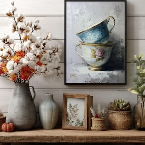 May include: A framed print of two stacked teacups with a blue and floral design. The teacups are on a wooden shelf with vases, a small pumpkin, and a framed picture. A cotton branch and orange flowers are in a gray vase.