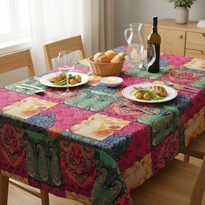Puede incluir: Un mantel colorido con estampado de cachemira en tonos rosa, verde y azul cubre una mesa de comedor de madera. La mesa está puesta con platos de comida, copas de vino y una cesta de pan, creando una escena de comedor vibrante.