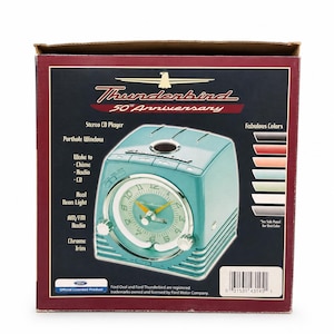 May include: A Thunderbird 50th Anniversary product box featuring a teal-colored stereo CD player with an analog clock face, chrome trim, and neon light. The box displays text including Stereo CD Player, Porthole Window, Wake to Chime, Radio, CD, Real Neon Light, AM/FM Radio, and Chrome Trim.