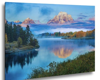 Puede incluir: Una impresión de paisaje que presenta una cordillera con picos nevados reflejados en un lago tranquilo. La imagen muestra un cielo vibrante, árboles verdes exuberantes y colorido follaje otoñal, creando una vista serena y pintoresca.