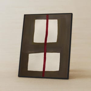 May include: Abstract art piece featuring two white rectangular shapes on a dark brown background, bisected by a vertical red line. The artwork is framed in a black border, creating a modern and minimalist aesthetic.