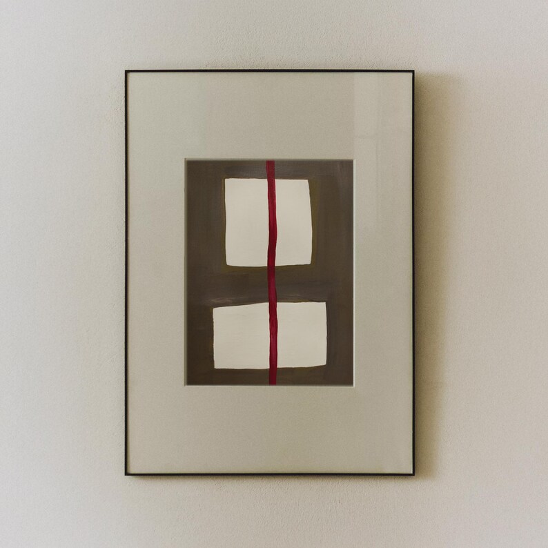 May include: Framed abstract art print featuring two white rectangular shapes stacked vertically, bisected by a vertical red line. The background is a muted brown, and the frame is a neutral off-white with a black border.