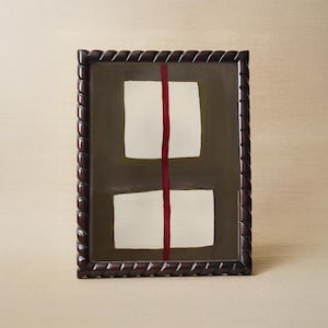May include: Framed abstract art featuring two white rectangular shapes on a dark brown background, bisected by a vertical red line. The frame is dark brown with a decorative rope-like edge. The artwork is a modern, minimalist design.
