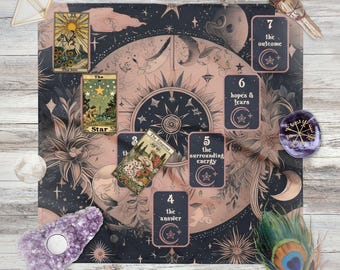 May include: A tarot card reading setup featuring a dark pink and navy blue mat with celestial and floral designs. Tarot cards are laid out, along with crystals, a feather, and a smudge stick. The cards include "The Sun," "The Star," and "The Empress."