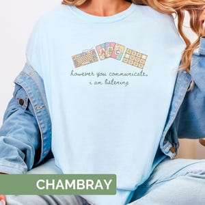 May include: Light blue t-shirt with the text "however you communicate, i am listening." The shirt features a keyboard, ABC blocks, and star-shaped designs. The word "CHAMBRAY" is printed at the bottom of the image.