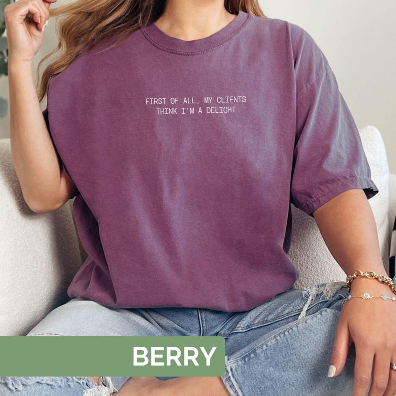 Puede incluir: Una camiseta de color bayas con el texto "FIRST OF ALL, MY CLIENTS THINK I'M A DELIGHT" en blanco. La camiseta es de color liso y tiene un corte relajado. La palabra "BERRY" se muestra en un rect&aacute;ngulo verde en la parte inferior.