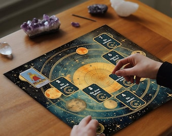 May include: A celestial-themed tarot card spread on a wooden table. The spread features a dark blue and gold design with planets, stars, and moons. Tarot cards are laid out, with the word "THEOS" visible on one card. Crystals and other decorative items are also present.