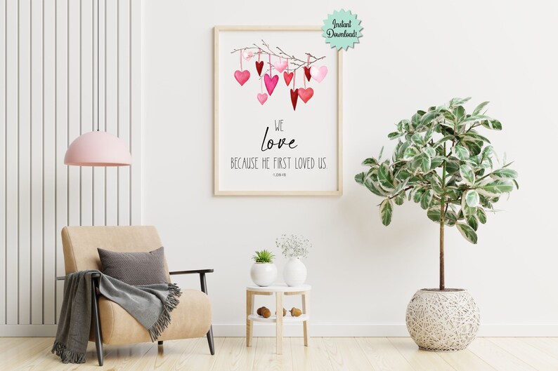 May include: Printable wall art with a watercolor illustration of pink hearts hanging from a branch. The text reads "We love because He first loved us 1 John 4:19".
