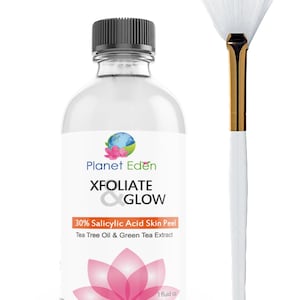 May include: A clear glass bottle with a black cap and a white label featuring the text "XFOLIATE & GLOW" and "30% Salicylic Acid Skin Peel." A white fan brush with a gold handle is next to the bottle. The bottle contains 30 ml.