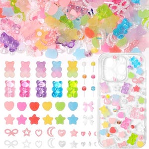 May include: A collection of colorful resin cabochons including gummy bears, hearts, stars, bows, moons, and lollipops, alongside a clear phone case decorated with these same miniature charms in a scattered, playful arrangement.