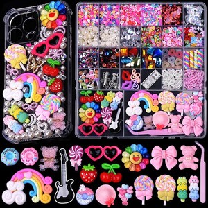 May include: A clear phone case decorated with colorful charms including rainbows, lollipops, flowers, and bears, alongside a multi-compartment storage box filled with assorted craft beads, charms, and a pair of pink tweezers for DIY decoration.