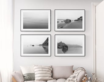 May include: A set of four black and white framed photographs of a beach scene with rocks and water. The photos are arranged in a grid pattern on a white wall.