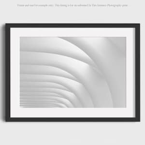 May include: Black and white photograph of a white, curved, architectural structure. The image is framed in a black frame.