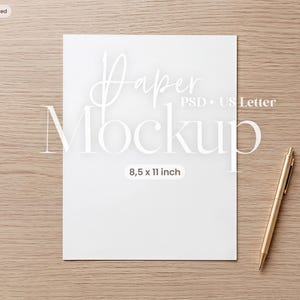 以下が含まれることがあります： 21.59 x 27.94 cmの白い長方形の紙で、Paper Mockup PSD US Letterという文字が印刷されており、紙の右側に斜めに配置された金色の金属製ペンが添えられています。