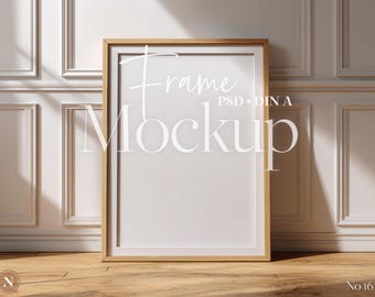 May include: A rectangular wooden frame mockup with a white interior, leaning against a white wall with molding. The text "Frame Mockup PSD DIN A" is displayed on the frame. The frame rests on a wooden floor.