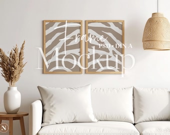 Può includere: Due cornici rettangolari in legno contenenti stampe con un motivo a strisce zebrate beige e bianco. Le cornici sono esposte su una parete sopra un divano bianco. Il testo "Frame Mockup PSD DIN A" è sovrapposto al centro delle due cornici.