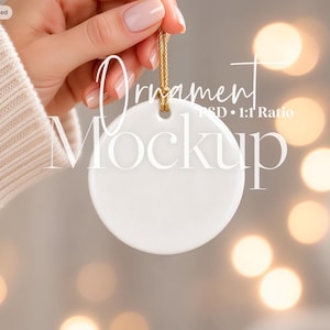 May include: A round, white ceramic ornament featuring a smooth, blank surface and a small hole at the top. A thin, gold-colored cord is looped through the hole for hanging. The text "Ornament Mockup PSD 1:1 Ratio" and "No 872" are visible.