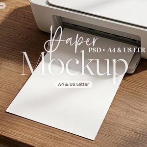 May include: A white printer with a blank sheet of paper extending from the tray. The text Paper Mockup PSD A4 & US LTR is overlaid in white script and serif fonts, with a small rectangular label reading A4 & US Letter centered on the page.