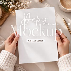 May include: A white rectangular paper mockup featuring the text Paper Mockup PSD A4 & US LTR and A4 & US Letter. The paper is held in a vertical orientation, showcasing a clean surface for design display, suitable for professional presentation.