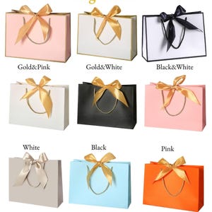 May include: Nine gift bags in various colors, each with a matching ribbon bow and rope handles. Colors include pink, white, black, champagne, Tiffany blue, and Hermes orange. Text on the image reads "Bag Colors."