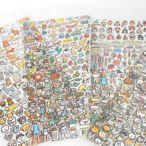 May include: Sheets of colourful stickers featuring dogs, cats, people, and objects such as food, gifts, and rainbows. The stickers have a cartoon style with black outlines and bright colours, ideal for scrapbooking or decorating.