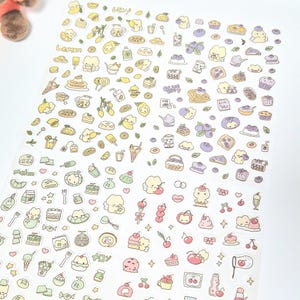 May include: A sheet of colourful stickers featuring various food illustrations. The stickers include lemons, cakes, ice cream cones, and other desserts. The stickers are in a cartoon style with a white background.