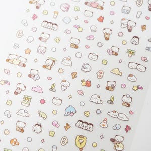 May include: A sheet of stickers with cartoon bears, dolphins, shells, and starfish in pastel colours. The stickers are on a clear background. The stickers have a sea theme.
