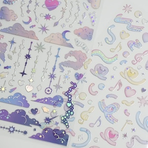 May include: Sheets of iridescent stickers featuring celestial and musical themes. Designs include clouds, stars, moons, musical notes, and hearts in shades of purple, pink, and blue. The stickers have a holographic effect, creating a shimmering appearance.