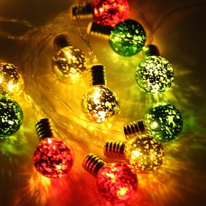 May include: A string of decorative globe lights with a speckled appearance. The lights are in shades of red, green, and gold, creating a festive ambiance. The bulbs are connected by a thin, clear wire, suitable for indoor decoration.