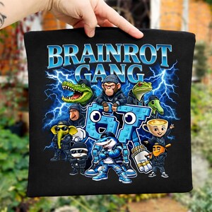 以下が含まれることがあります： 黒色のトートバッグ。青色の「BRAINROT GANG」の文字と、様々な動物のキャラクターの漫画のグラフィックが描かれています。キャラクターには、ワニ、猿、カエル、サメなどが含まれており、すべてストリートウェアの服装で、青い稲妻の背景が描かれています。
