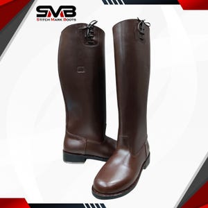 Könnte beinhalten: Ein Paar hohe, braune Lederreitstiefel. Die Stiefel haben ein klassisches Design mit runder Spitze, glatter Oberfläche und Schnürsenkeln oben. Der Markenname "STITCH MARK BOOTS" ist sichtbar.