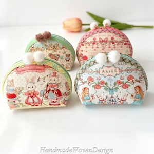 May include: Four semi-circular pouches with kiss-lock closures topped with white pom-poms. The pouches feature printed illustrations of rabbits, cats, and Alice in Wonderland characters, accented with plaid and floral patterns in pastel colors.
