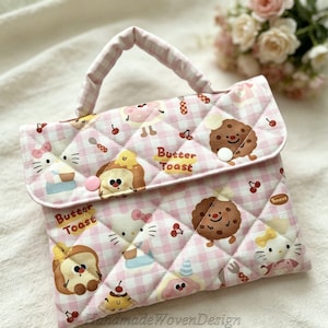 May include: A quilted pink and white checkered bag with a handle, featuring cartoon illustrations of toast, cookies, and other treats. The bag has a button closure and the words "Butter Toast" are printed on it.