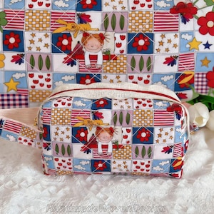 Puede incluir: Un neceser acolchado con un colorido diseño de patchwork con personajes de dibujos animados, flores y estrellas. La bolsa tiene una parte superior blanca con cremallera roja y un asa a juego. El texto "HandmadeWovenDesign" está en la parte inferior.