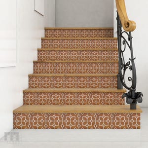 K&ouml;nnte beinhalten: Eine Treppe mit Holzstufen und Setzstufen, die mit gemusterten Fliesen verziert sind. Die Fliesen weisen ein sich wiederholendes Blumendesign in Braun- und Wei&szlig;t&ouml;nen auf. Ein schwarzes schmiedeeisernes Gel&auml;nder mit einem Holzhandlauf ist sichtbar.