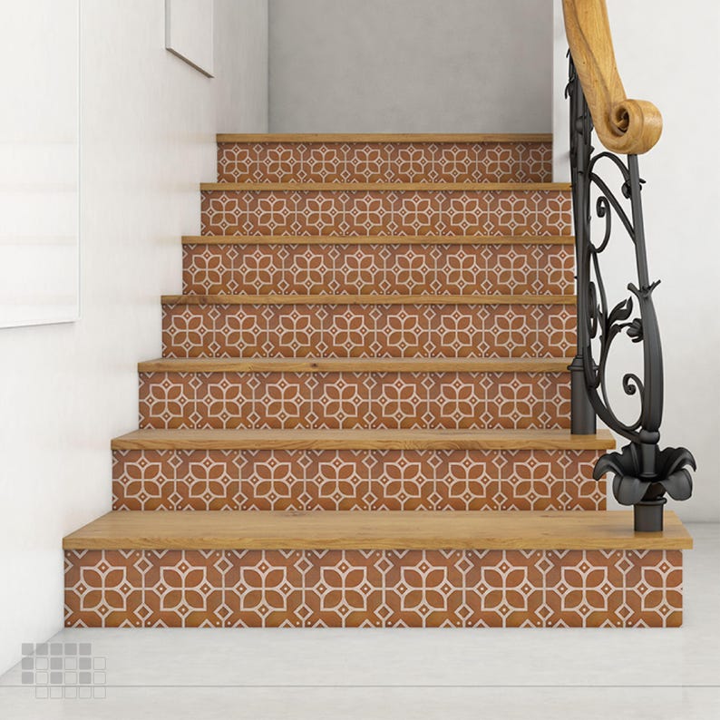 K&ouml;nnte beinhalten: Eine Treppe mit Holzstufen und Setzstufen, die mit gemusterten Fliesen verziert sind. Die Fliesen weisen ein sich wiederholendes Blumendesign in Braun- und Wei&szlig;t&ouml;nen auf. Ein schwarzes schmiedeeisernes Gel&auml;nder mit einem Holzhandlauf ist sichtbar.