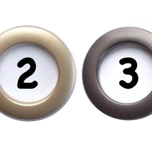 Pu&ograve; includere: Quattro occhielli rotondi per tende in argento, oro, grigio e nero. Ogni occhiello ha un centro bianco con un numero nero: 1, 2, 3 e 4. Gli occhielli sono progettati per tende.